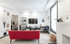 white family room with large picture window and white brick fireplace and tray ceiling with recessed lighting after renovation