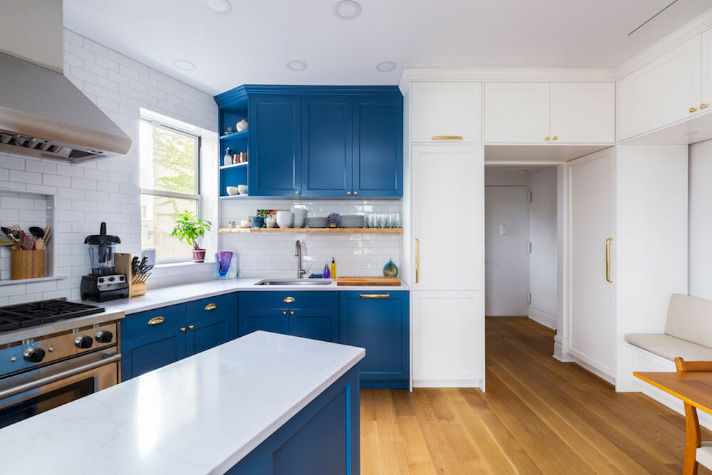 white wall kitchen with bright blue cabinets and stainless steel appliances and hardwood floors after renovation