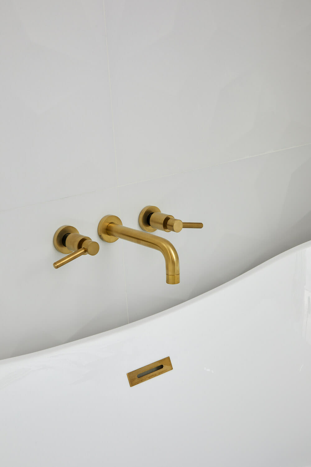 bathroom gold faucet and fixtures and rectangular overflow cover after renovation