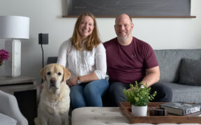 happy couple sitting on a gray couch with their dog after renovation