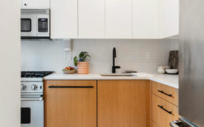 white quartz countertop with undermount sink and black faucets and golden oak and white cabinets and stainless steel appliances after renovation