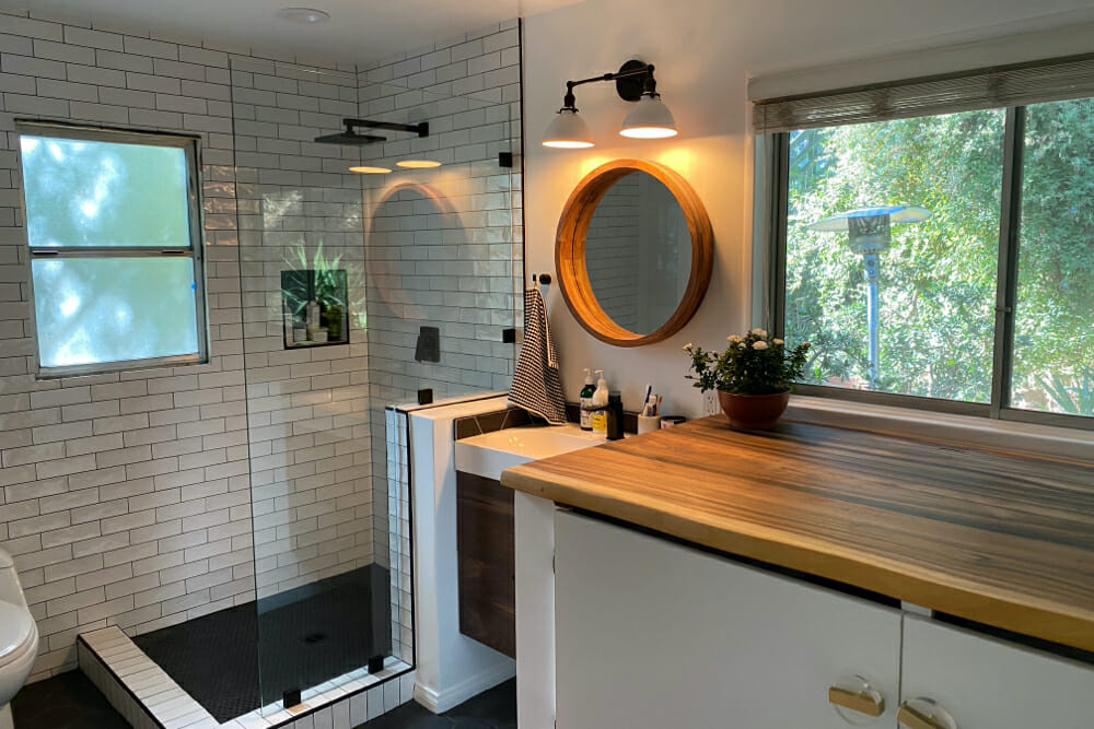 Image of a renovated bathroom with white tile and walk-in shower