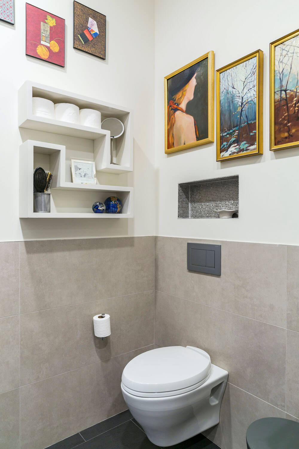 Image of a wall hung toilet surrounded by art collection