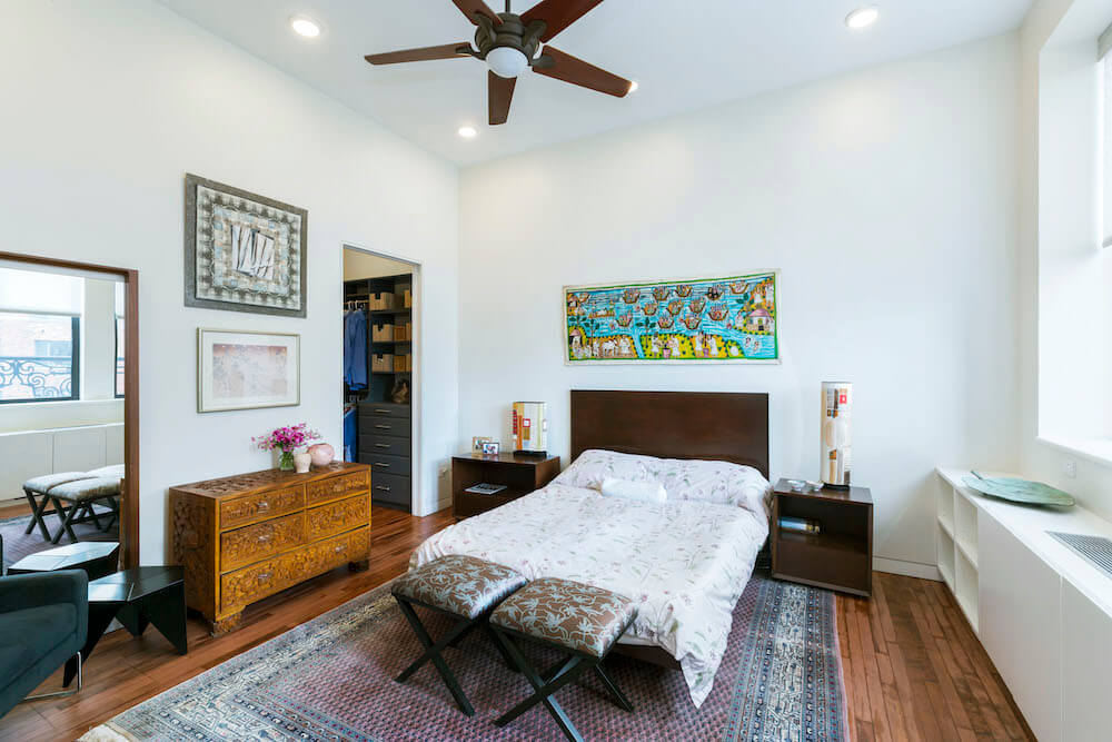 Image of a master bedroom with art collection and ceiling fan