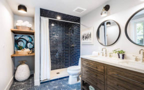 bathroom with black shower tile and double sink vanity