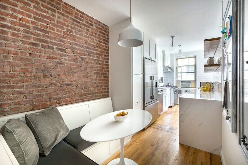 Image of exposed brick wall in dining area with view of white kitchen