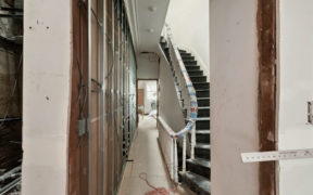 narrow passage way with staircase and white floor during renovation