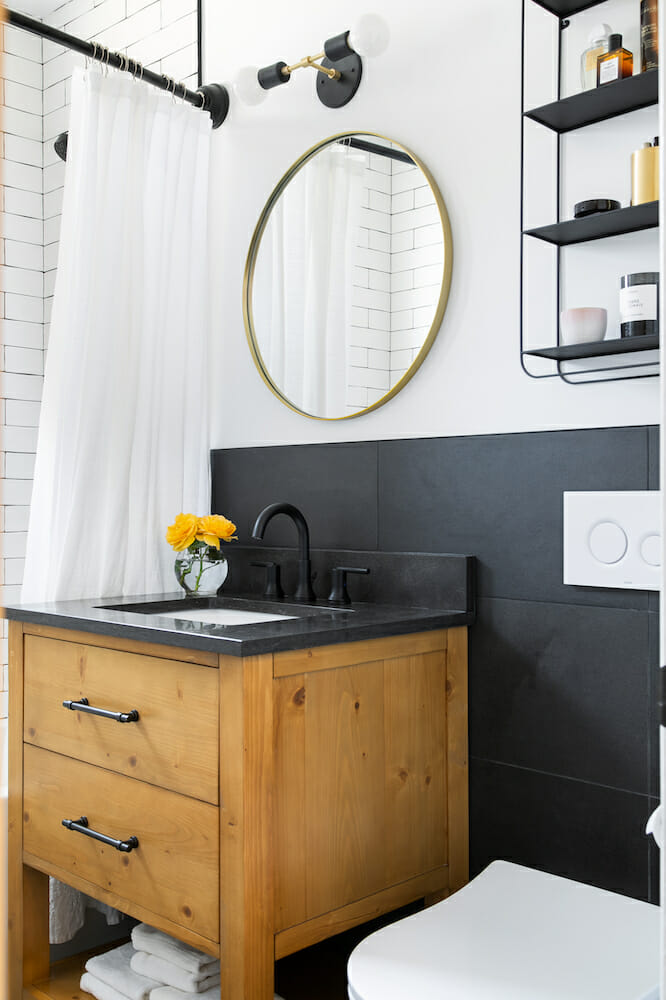 A modern bathroom with white walls, gray tile and wooden vanity