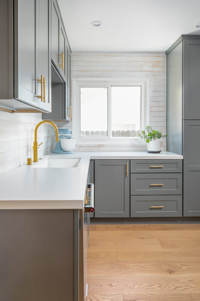 Image of kitchen cabinets with brass fixtures and white counters