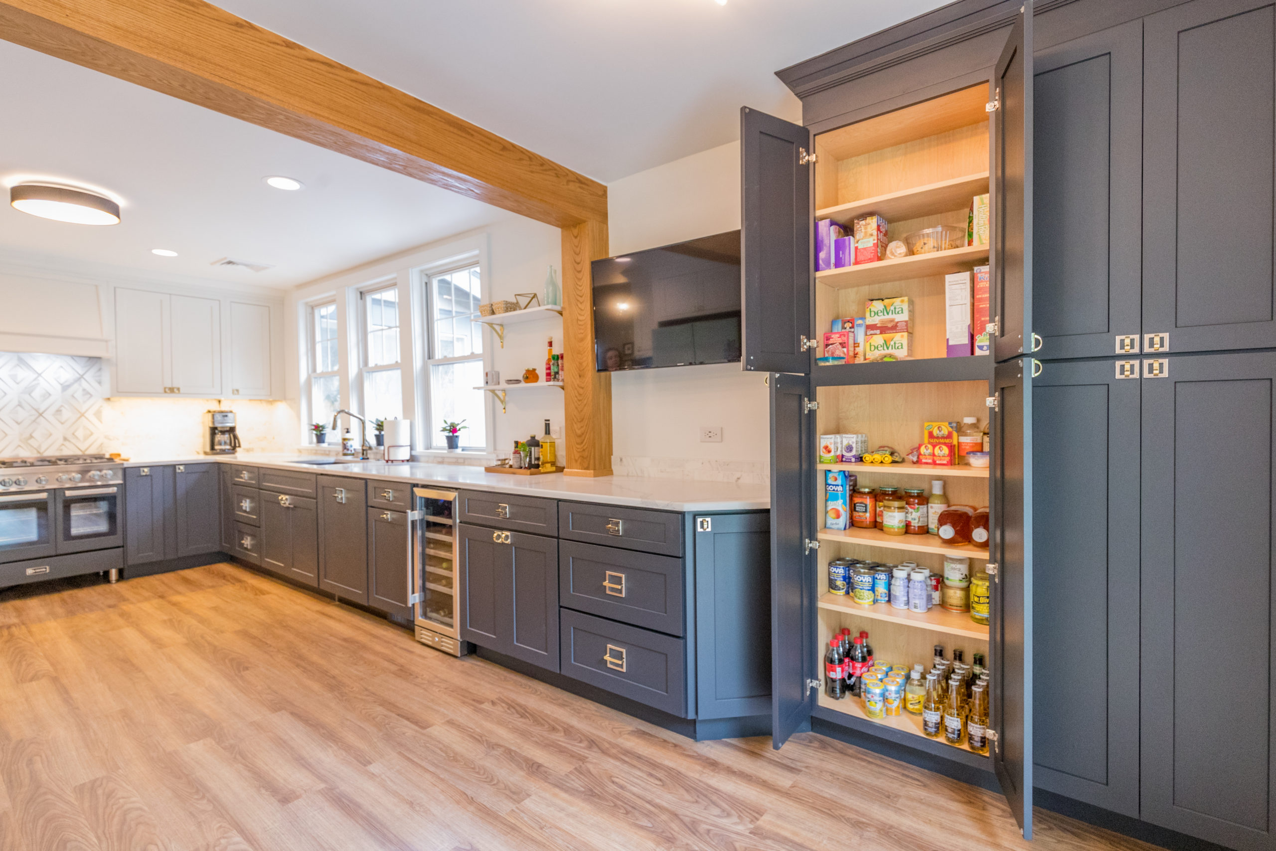 gray kitchen cabinets in a large kitchen with white countertop and large pantry shelf after renovation