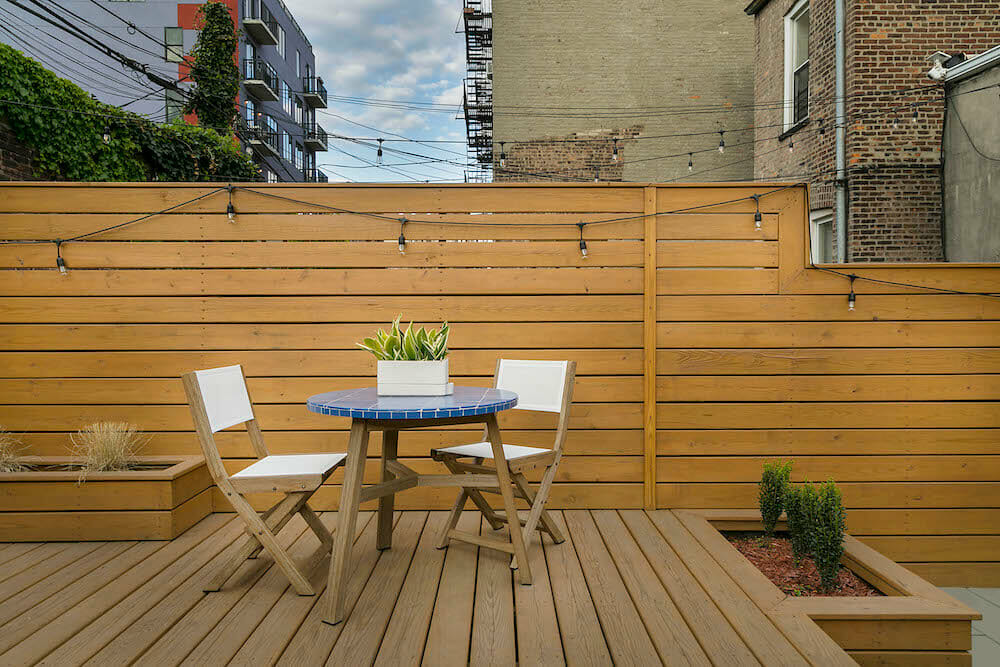 Brown wooden deck with horizontal fencing and patio table and chairs after renovation