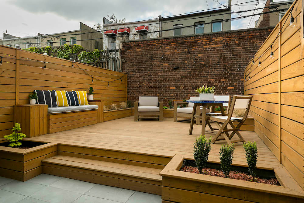 Small backyard deck with inbuilt seating and brick wall background after renovation