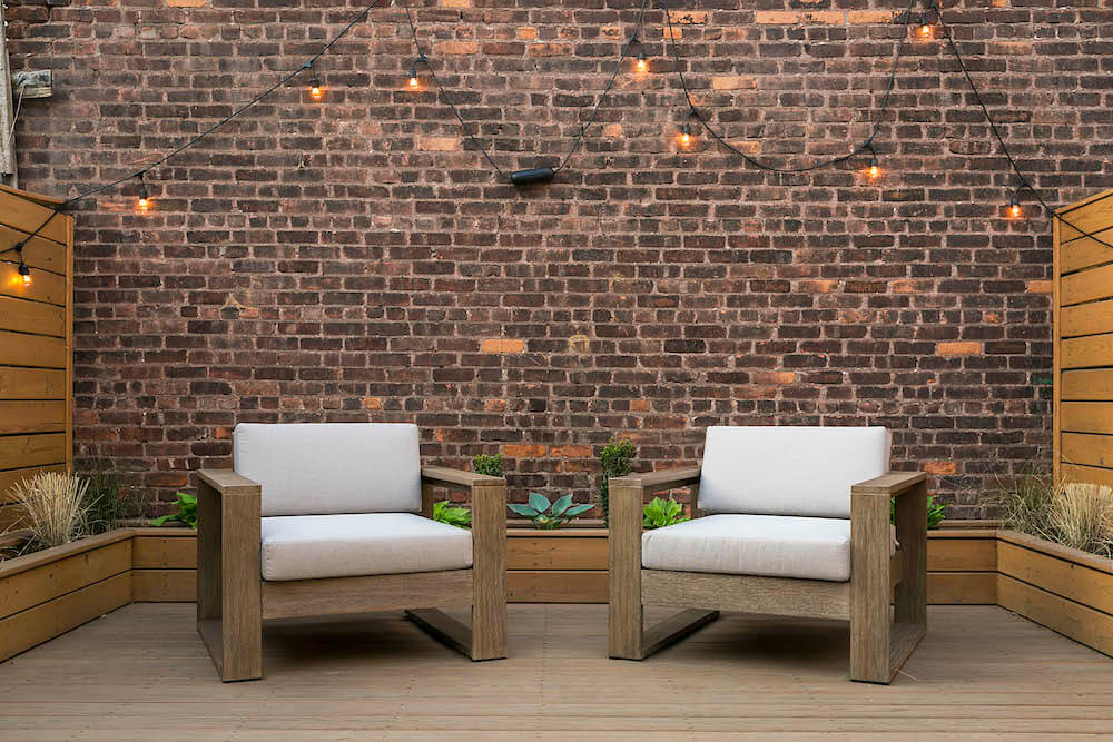Two white couches in the deck with the old brick wall building in the background after renovation