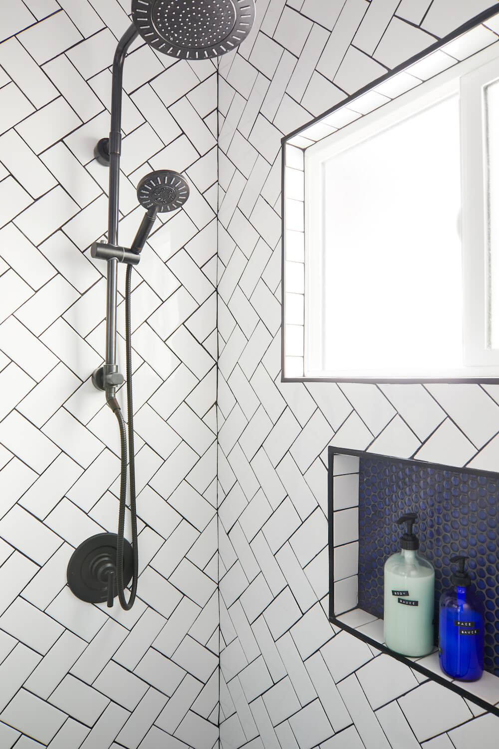 white herringbone tile with black grout in blue bathroom remodel in los angeles