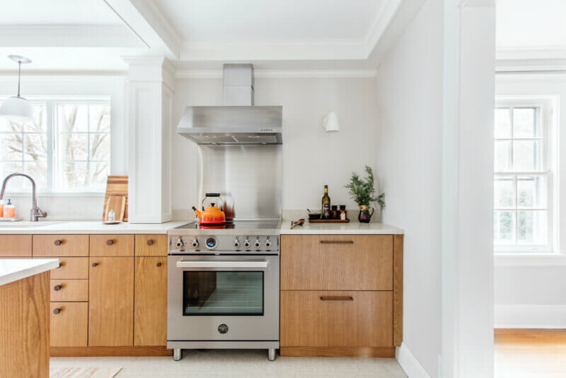 brown kitchen cabinets in a white walled kitchen with silver appliances after renovation