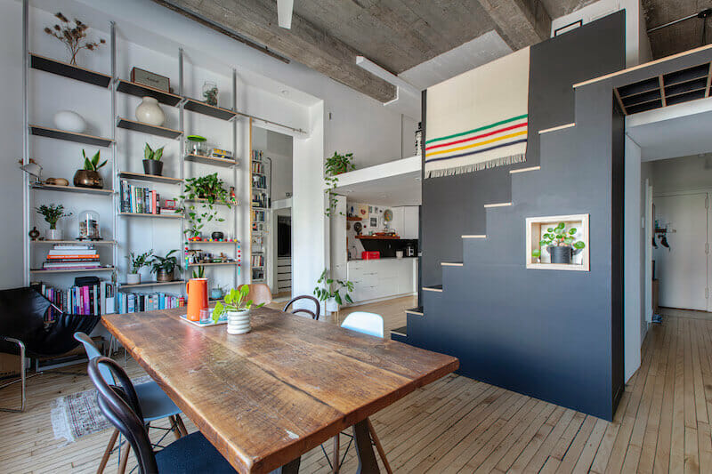 Dining area with open shelving unit overlooking the black staircase leading to the loft after renovation