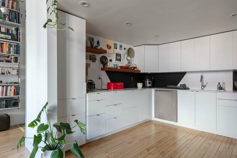 White open kitchen with closed cabinets and a tall shelf unit after renovation