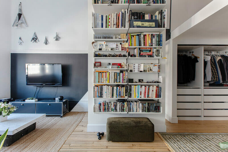 Open bookshelf between open wardrobe and living room after renovation