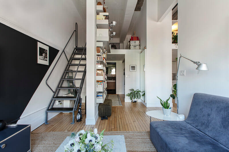 White living area with industrial use staircase and open shelf after renovation