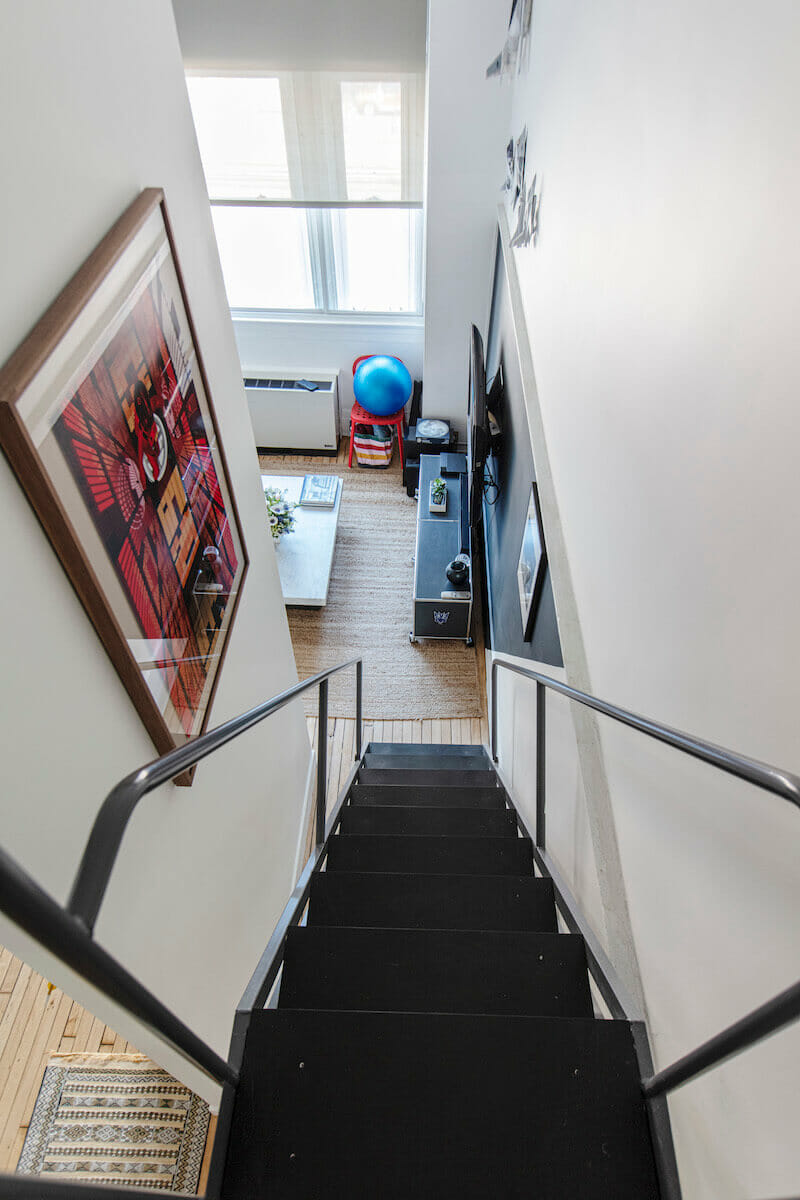 black staircase leading to the living area with wooden flooring after renovation