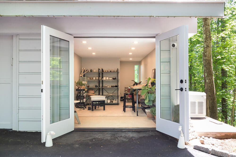 garage converted to pottery or art room with see through glass french doors and recessed lighting and concrete floors after renovation