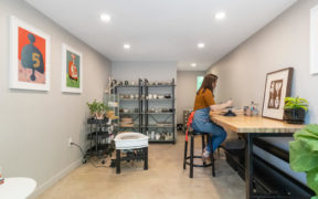 Grey Ceramic Art Studio with poured concrete flooring, wooden work bench and a minimal black storage, view from entrance