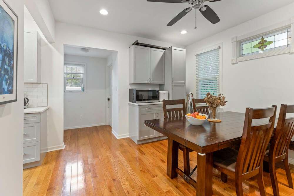 White dining space with dining table on a hardwood floor after renovation
