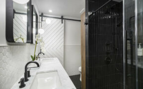 Remodeled bathroom in Brooklyn, NYC with double vanity, barn door and black tiled shower