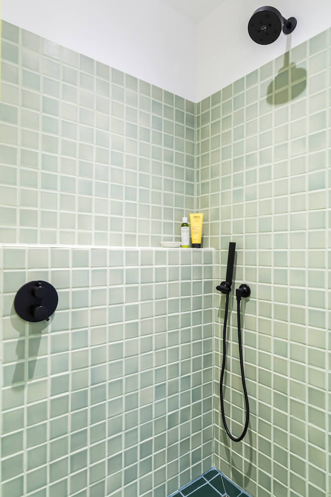 Sea green shower area with black bathroom fitting and a built in ledge after renovation