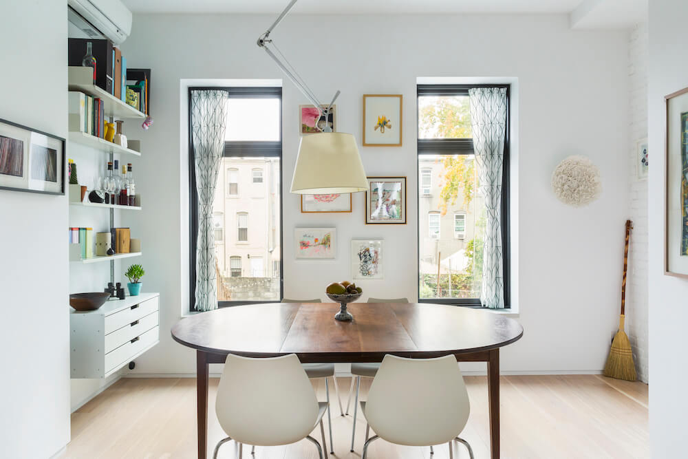 White dining nook with open shelving and double windows after renovation