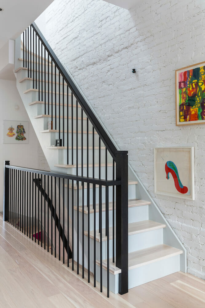 White staircase with black railing and white wall with art work after renovation