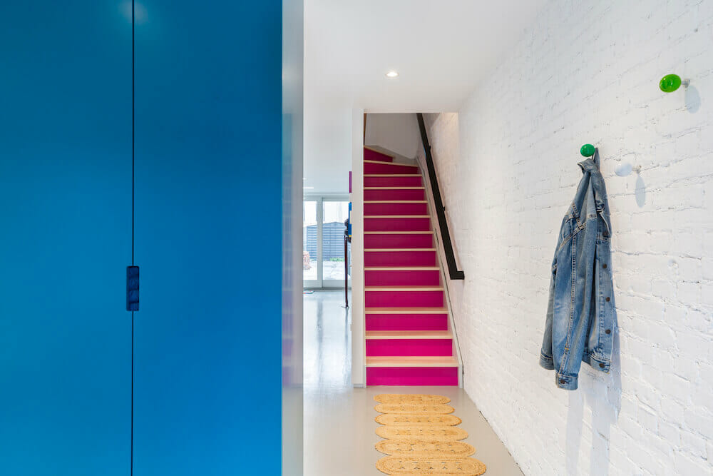 Blue closed coat closet with pink staircase and green coat hangers
