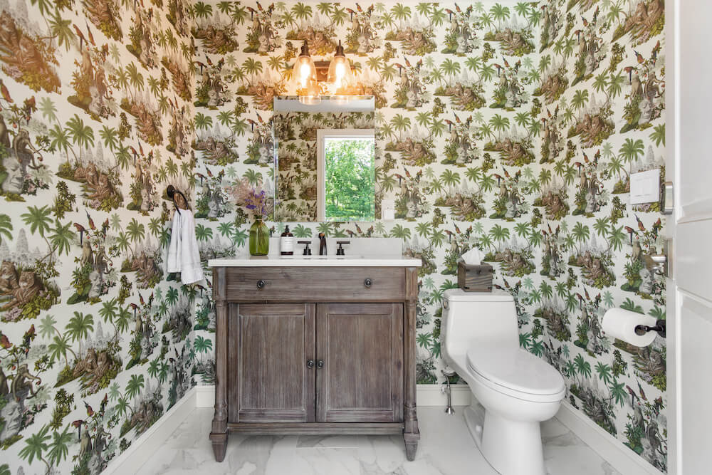 powder room with white floor tiles and colorful whimsical wallpaper after renovation