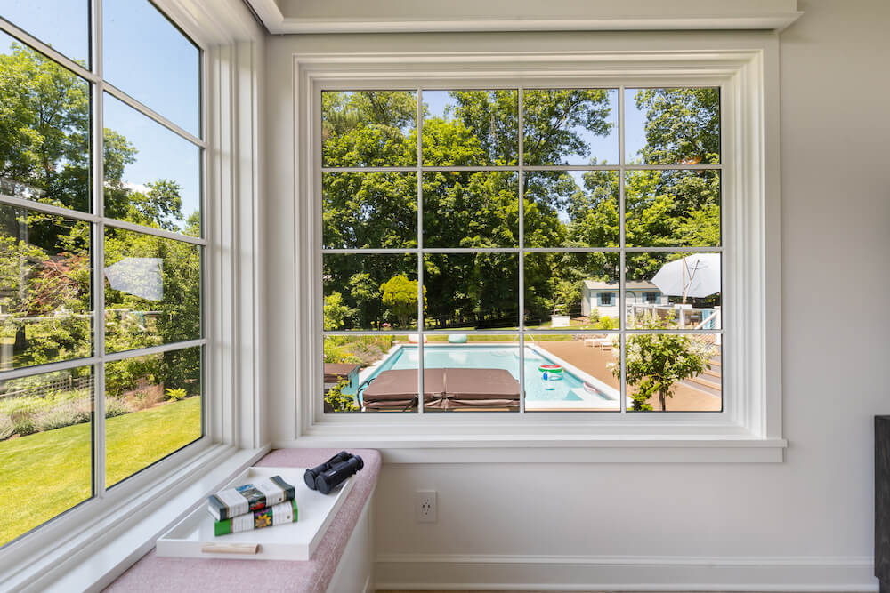 large window frame with grids overlooking swimming pool and backyard after renovation
