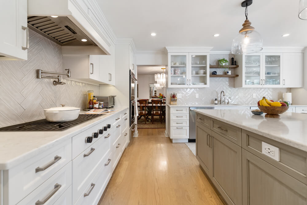 white kitchen cabinets with electric smooth top range and hood and island with pendant lights after renovation