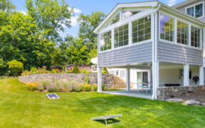 two story porch and sunroom with landscaped backyard after renovation