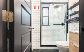black and white bathroom with subway tiles and black honeycomb or hexagon floor tiles and vanity and walk-in shower after renovation