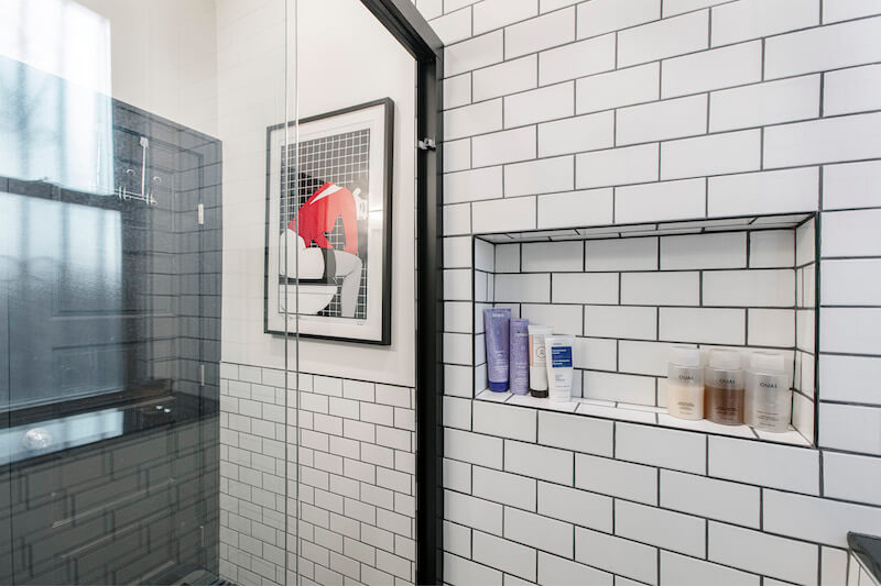 black and white walk-in shower with subway tiles and in-built shelf and sliding door after renovation