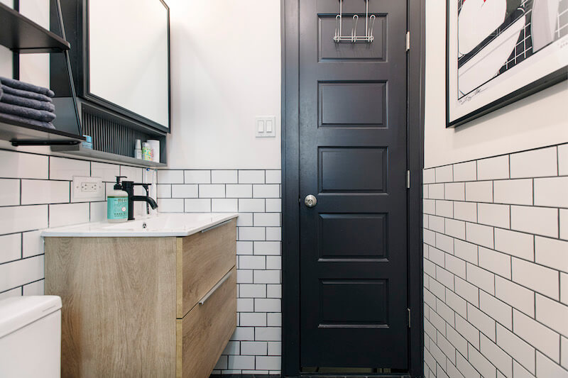 small black and white bathroom with vanity and wall mounted medicine cabinet with mirror and subway tiles after renovation
