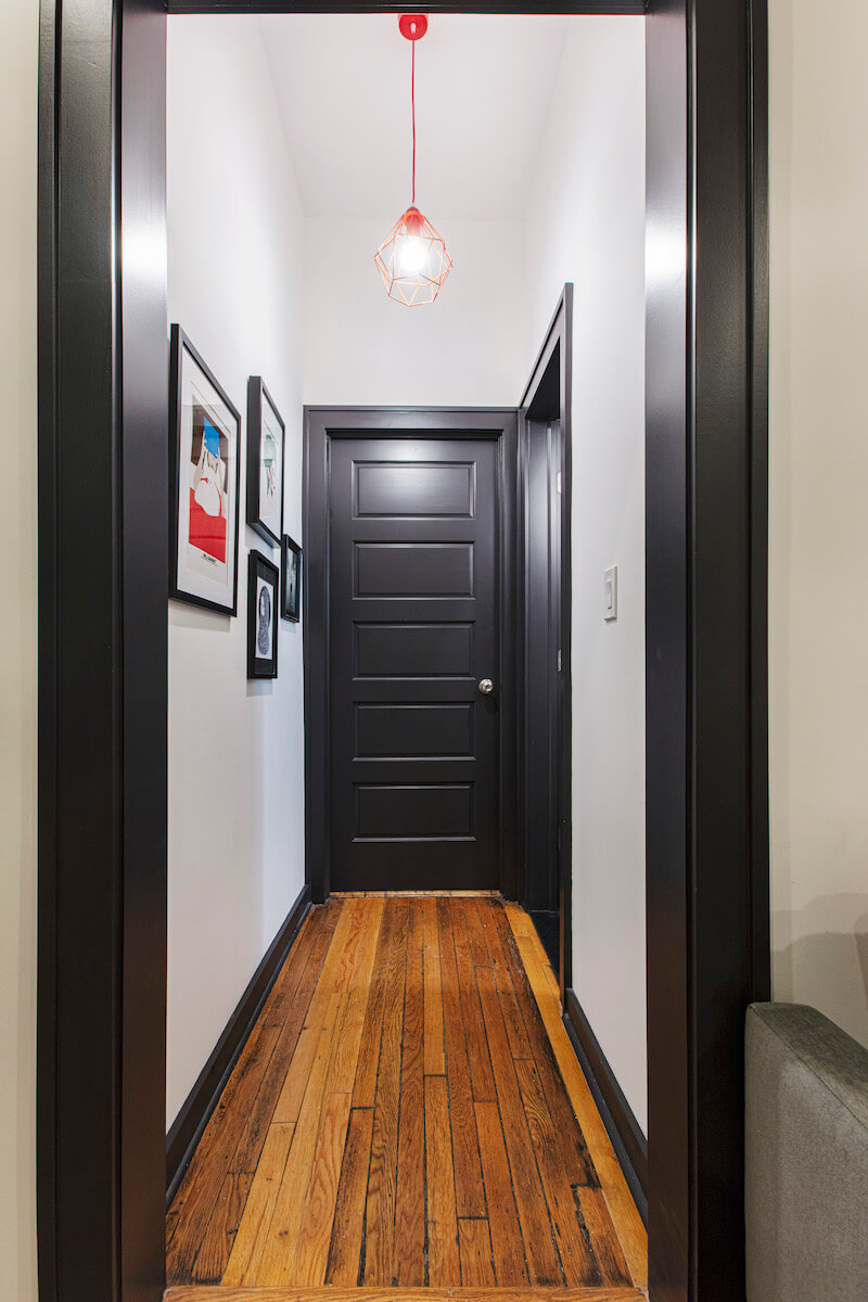 hallway with hardwood floors pendant light and dark base shoe molding after renovation