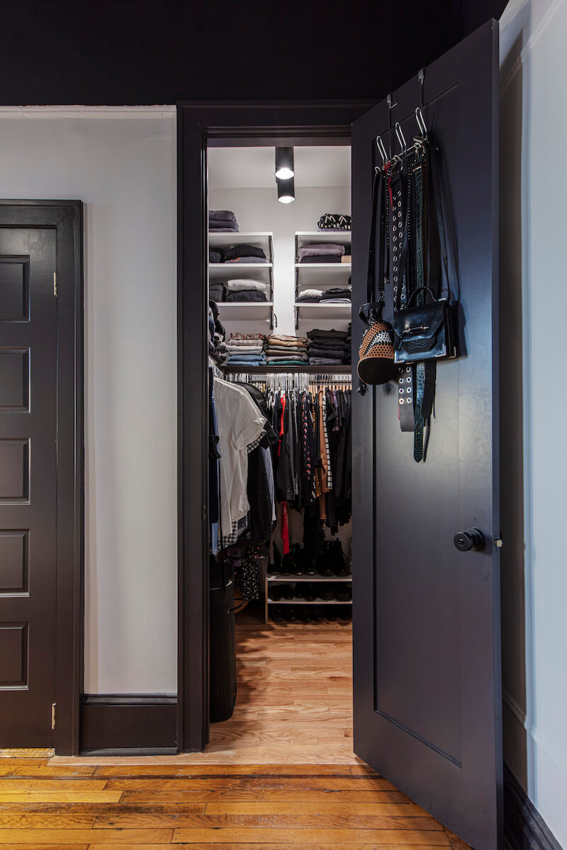 small walk-in closet with door and hardwood floors and track lights after renovation