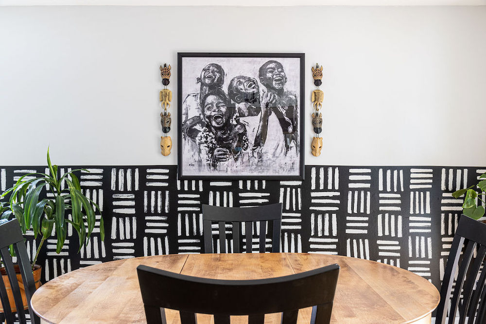 Breakfast nook with patterned half wall paper and painting of laughing children after renovation
