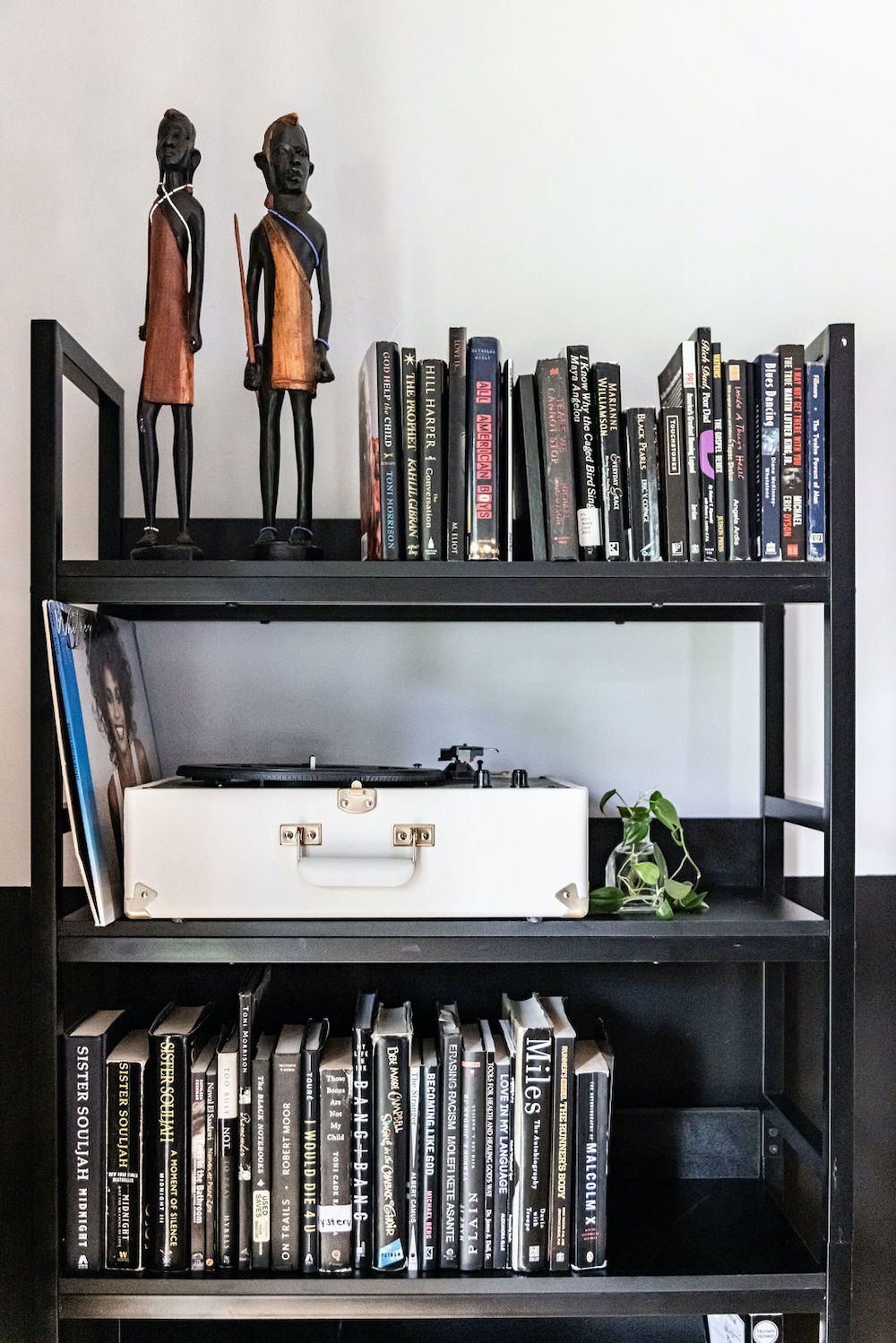 Black shelving unit with books and portable vinyl record player after renovation