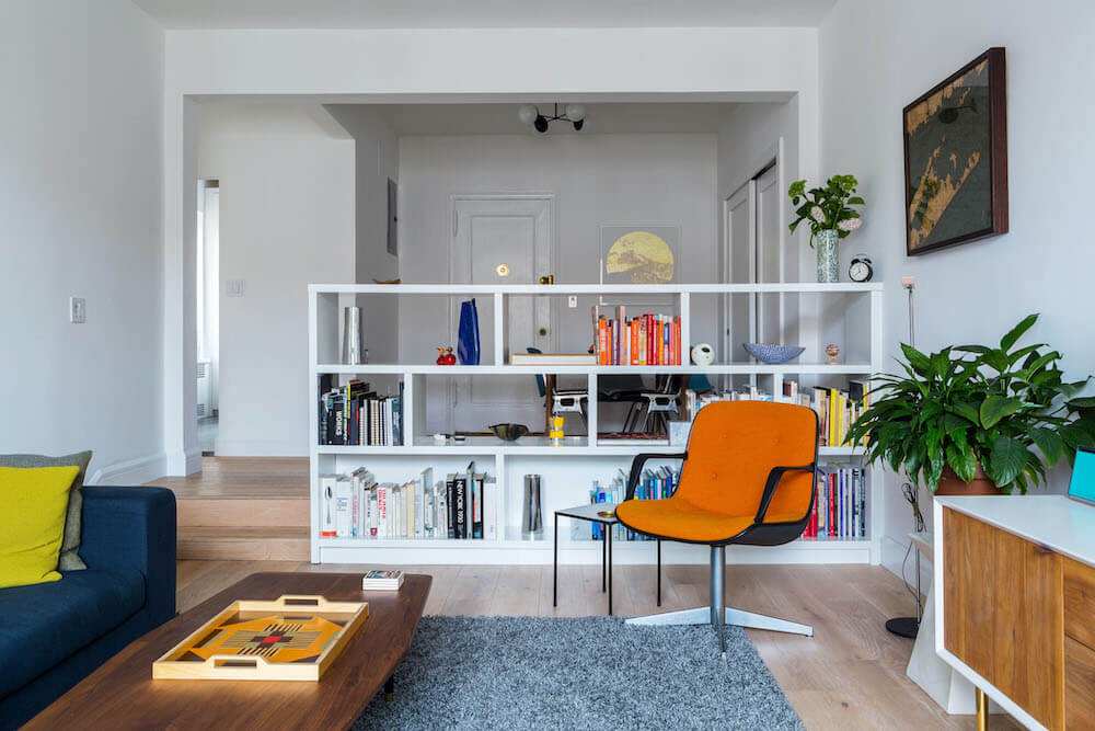open living and dining with hardwood floors and white walls and half wall book shelves as room divider partition after renovation