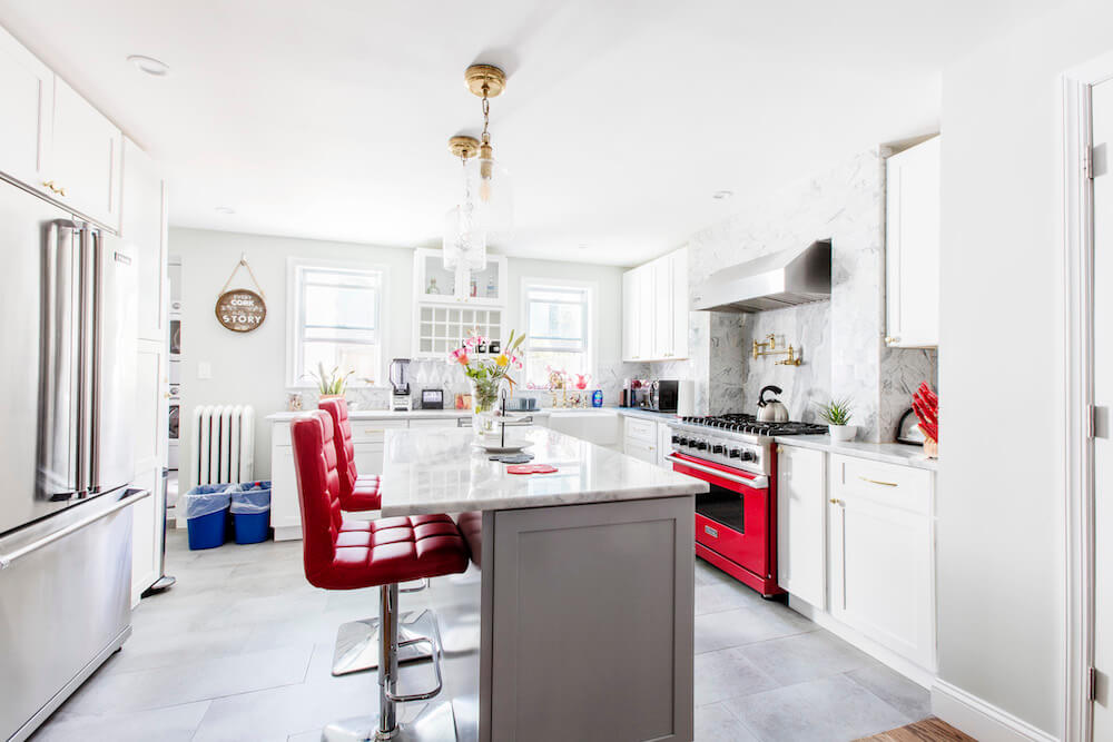 Large white kitchen with kitchen island and red bar stools after renovation
