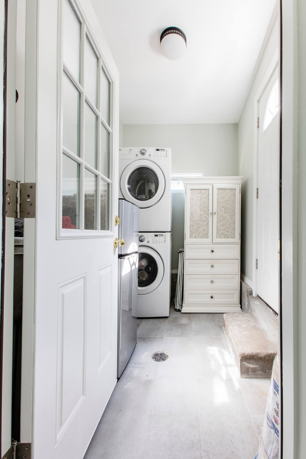 Door opening into laundry room with stacked washer and dryer, with white pantry storage