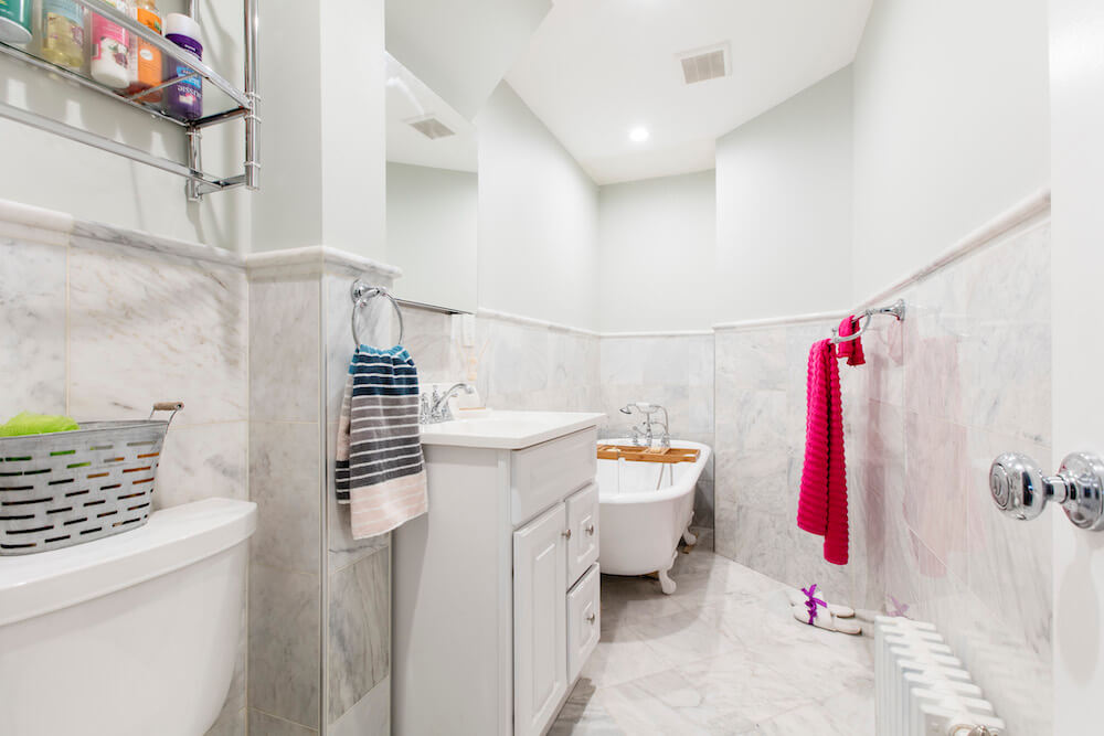 Remodeled bathroom with soaking bathtub, gray-white tile floors, and a white bathroom vanity
