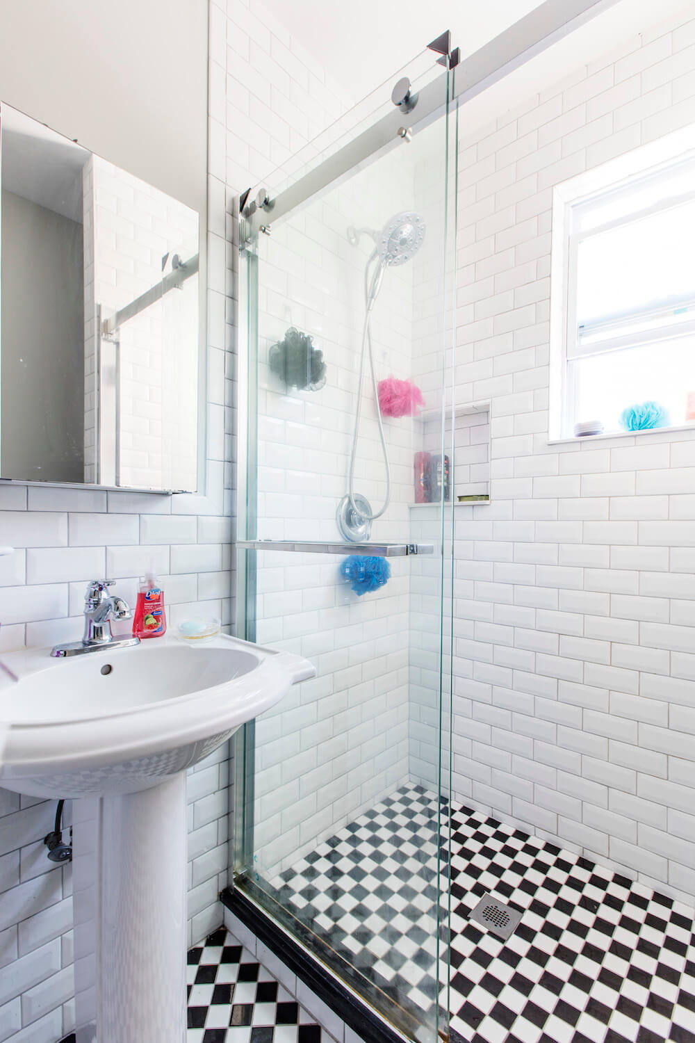 Small white bathroom with walk-in shower separated by glass separator and checkered tiles after renovation