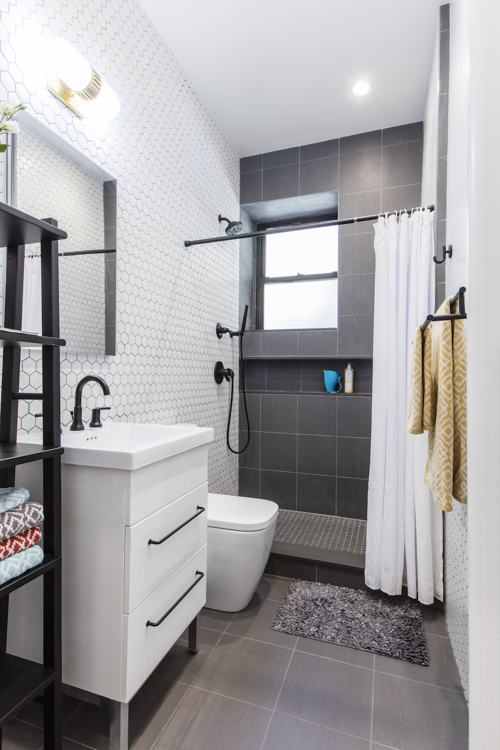 Bathroom with white tile walls, walk-in shower with gray tile and white bathroom vanity