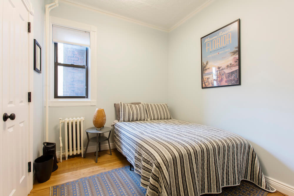 Light blue bedroom with a striped bed sham and Florida poster